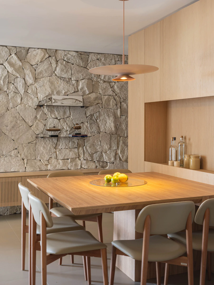 Walnut dining table and chairs against a travertine stone wall