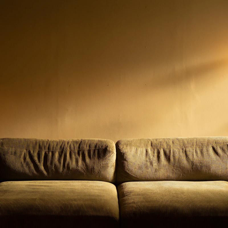 Ochre corduroy sofa against a sunlit plaster wall