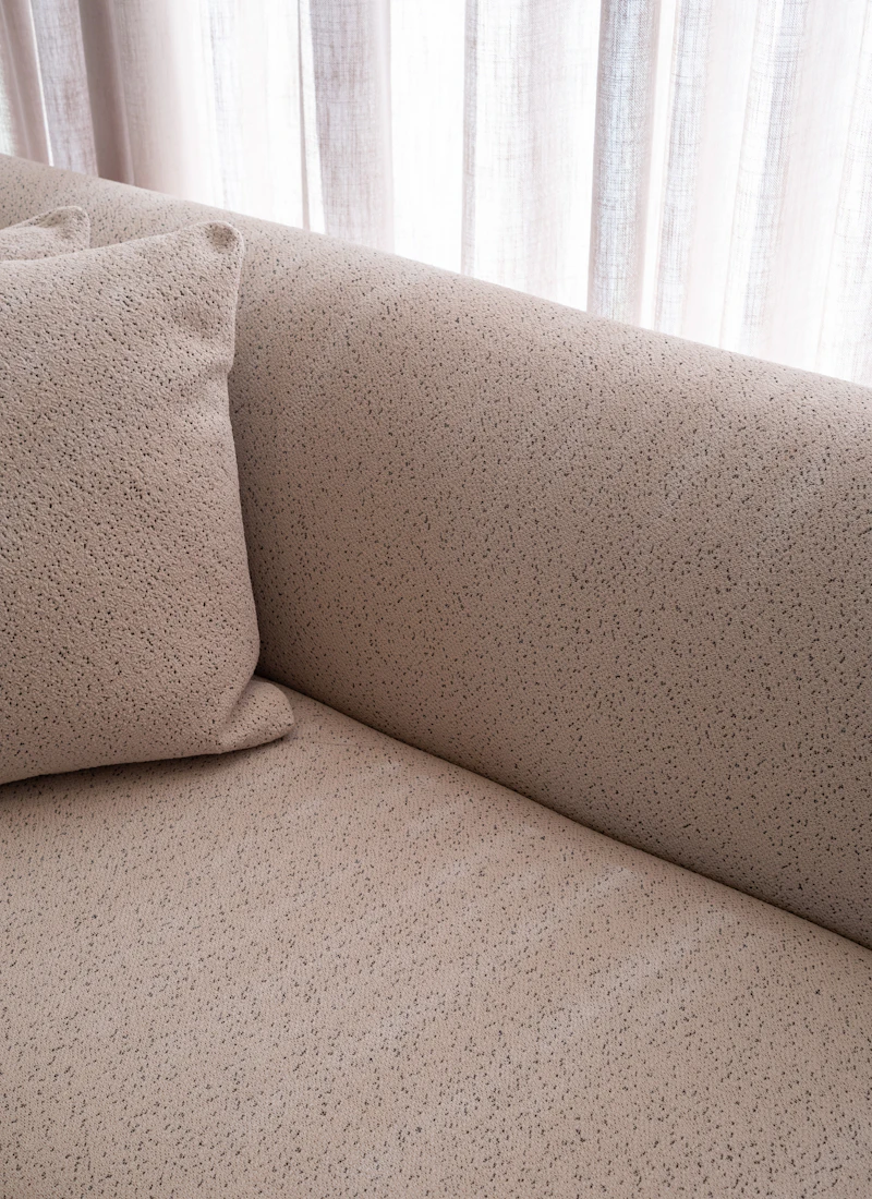 Textured beige linen sofa detail with sheer curtains